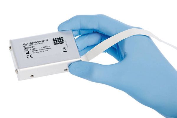 A hand with disposable glove holds a fluorescence detector.